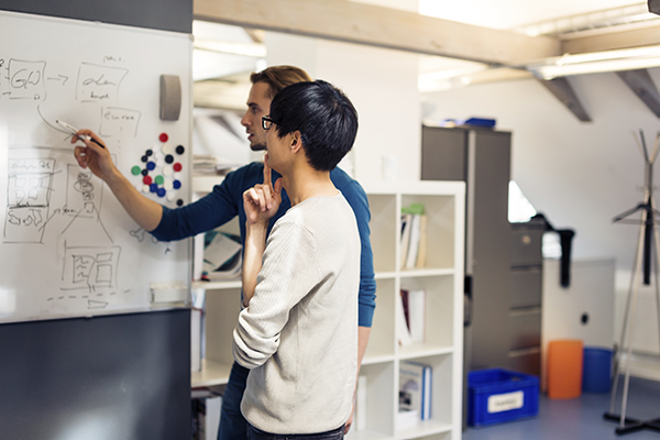 Systems engineers diagramming on a whiteboard