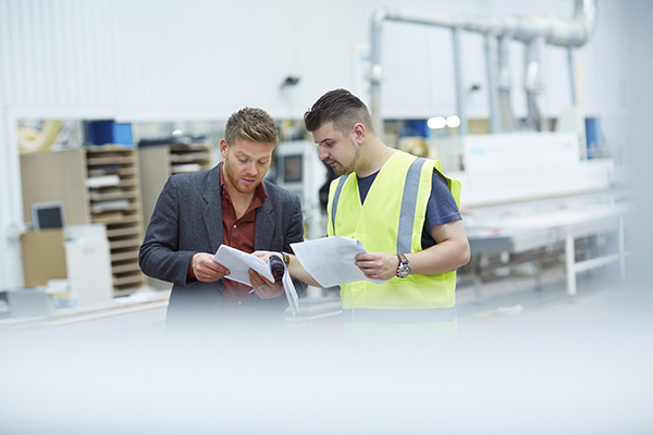 Two men comparing notes in a warehouse